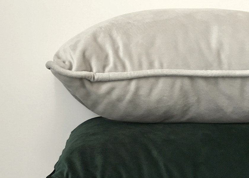 Soft velvet cushions stacked against a pale wall
